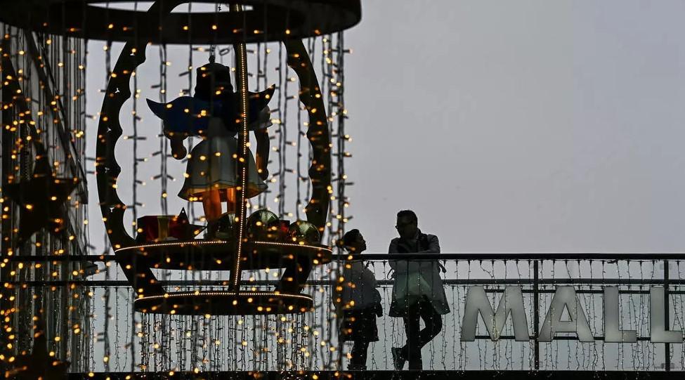 Customers stand on a balcony next to Christmas decorations in a shopping mall in Berlin. - Avaz