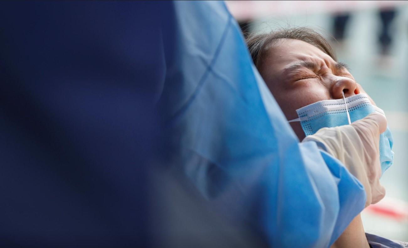 A woman reacts as a health worker uses a swab to collect a sample at a makeshift community testing centre for the coronavirus disease (COVID-19), in Hong Kong, China February 17, 2021. - Avaz